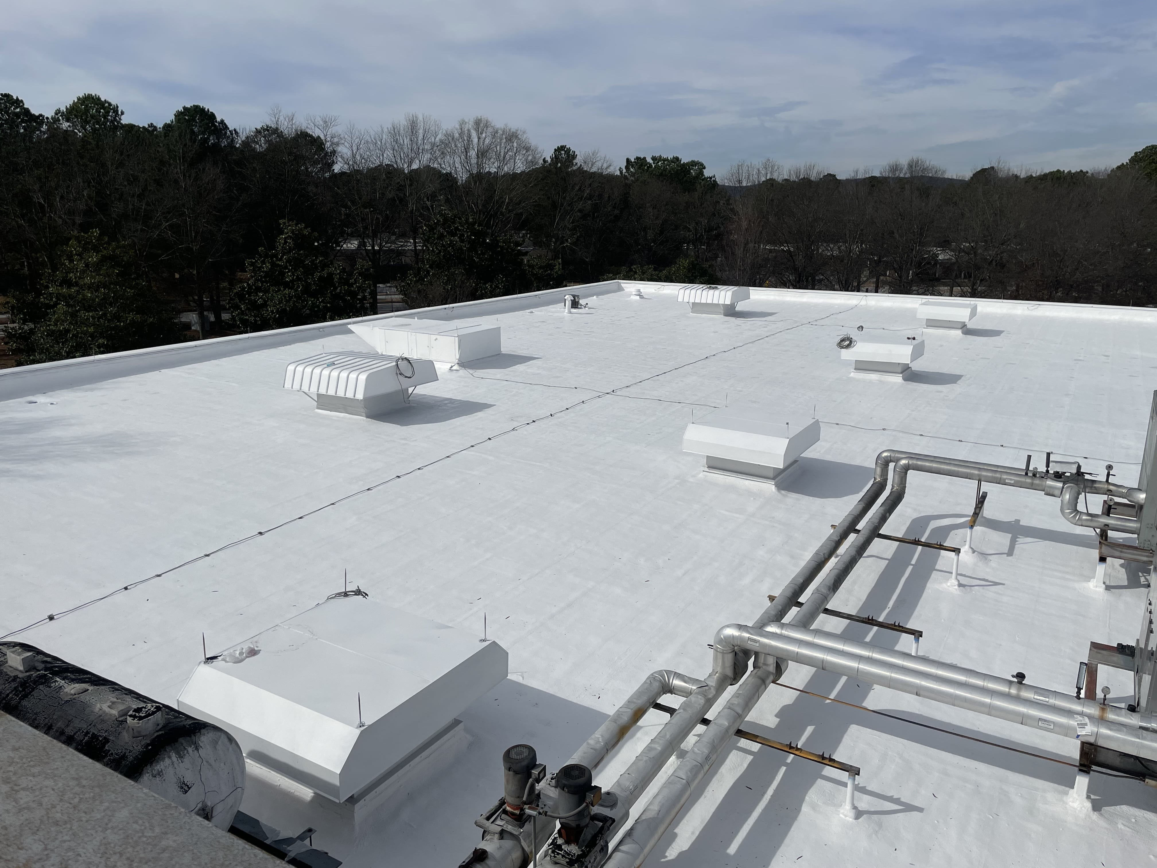 Professional spray foam roofing application in progress showing workers applying seamless waterproof barrier for superior insulation and energy efficiency